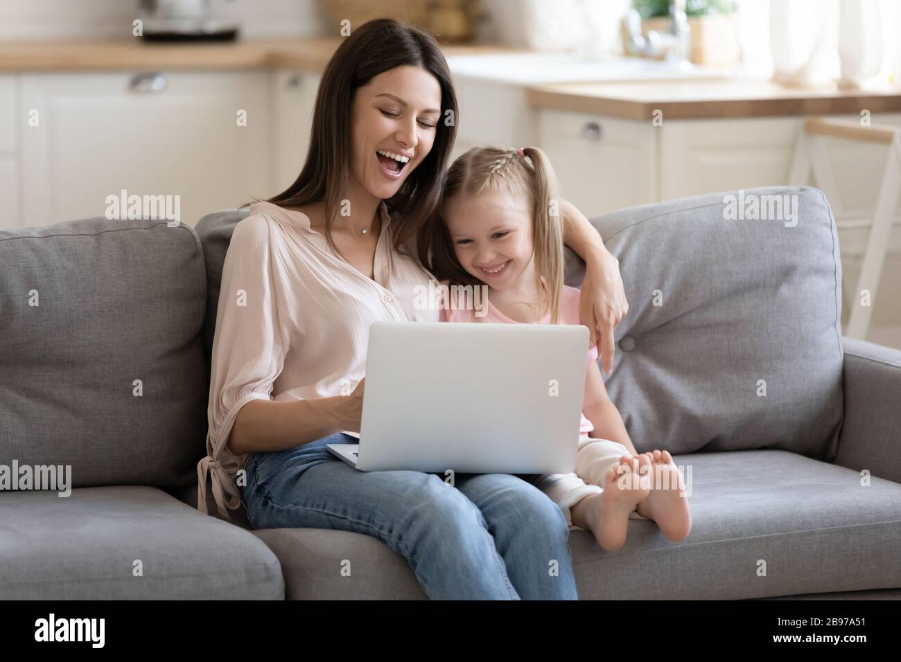 Overjoyed mom and daughter watch funny video on laptop Stock Photo - Alamy