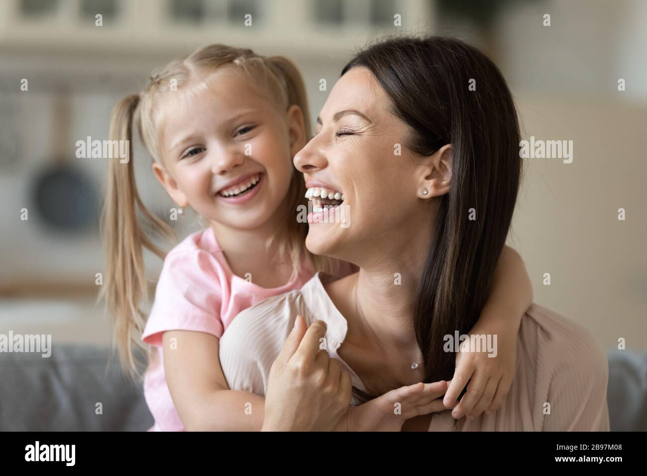 Happy mom and daughter cuddling playing at home Stock Photo