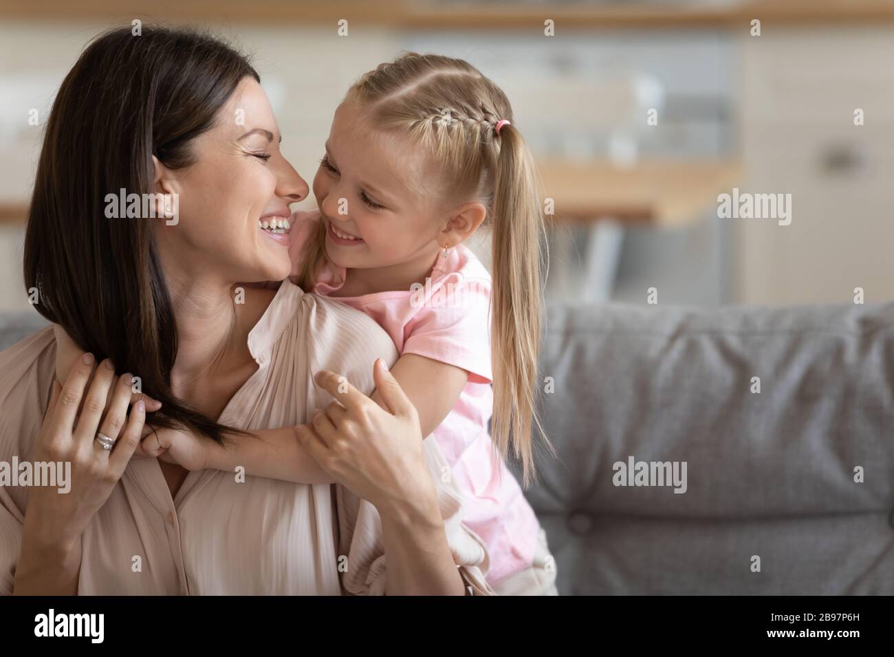 Little girl and young mom have fun cuddling at home Stock Photo