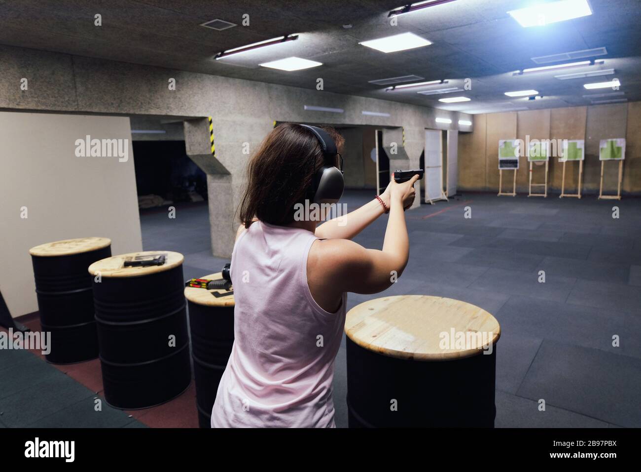 Girl in headphones shoots a gun in shooting range Stock Photo Alamy