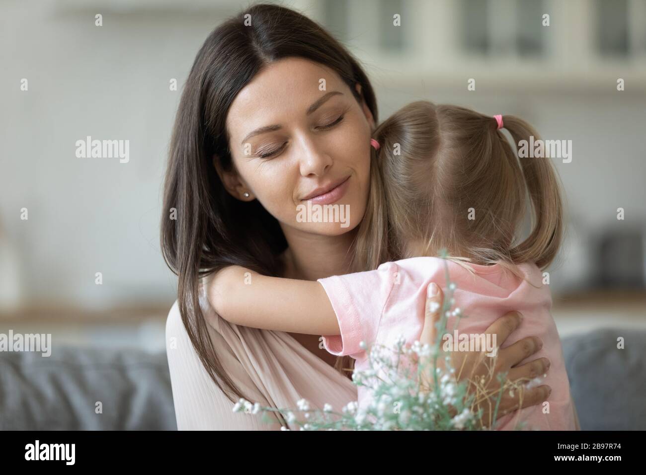 Little daughter hug young mom presenting flowers Stock Photo