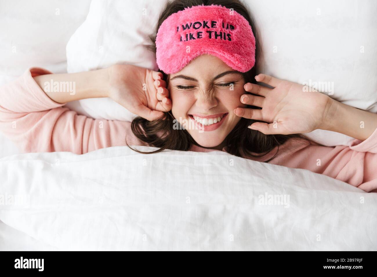 Cheerful lovely young girl wearing pajamas laying in bed at the bedroom