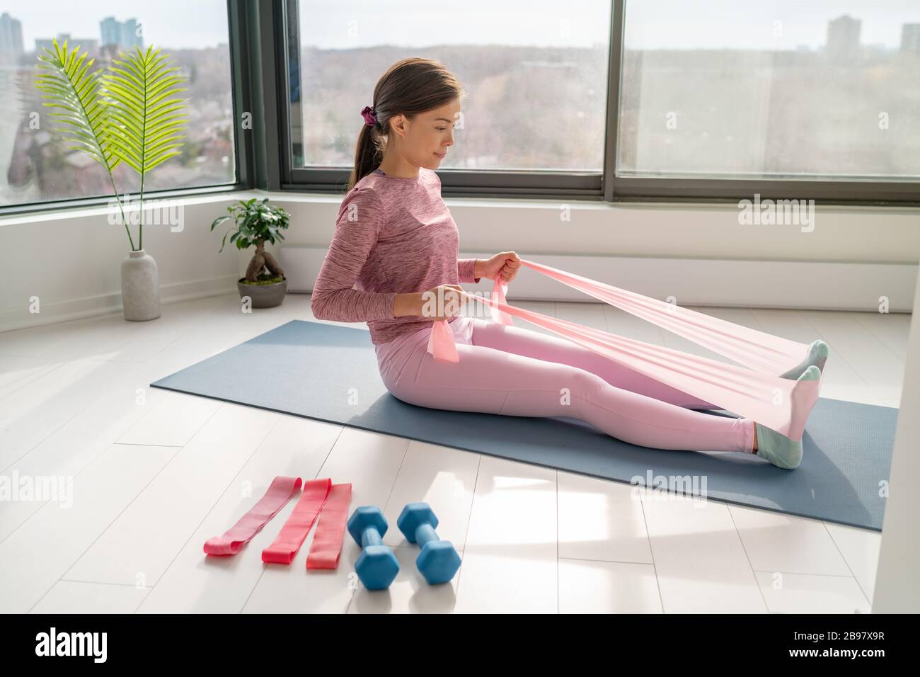 Home workout with resistance band fitness Asian woman training back muscles  with rowing arm movement using rubber bands on yoga mat floor exercises  Stock Photo - Alamy