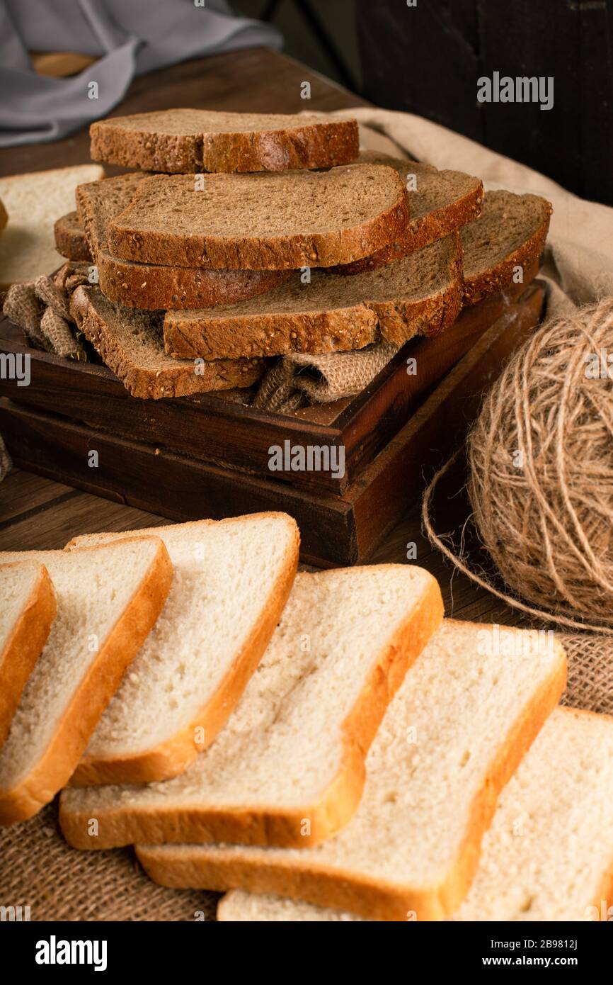 Slices of dark and white bread in box and on tablecloth Stock Photo