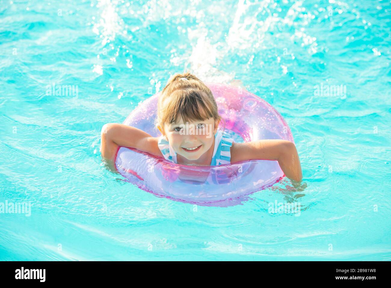 Little Girl Lying In Swimming Pool Learning To Swim On Inflatable