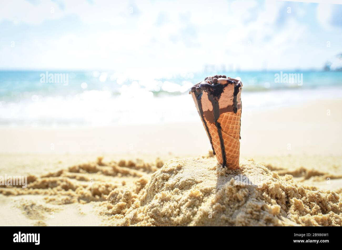 Ice cream cone on sand beach background / Melting ice cream on beach