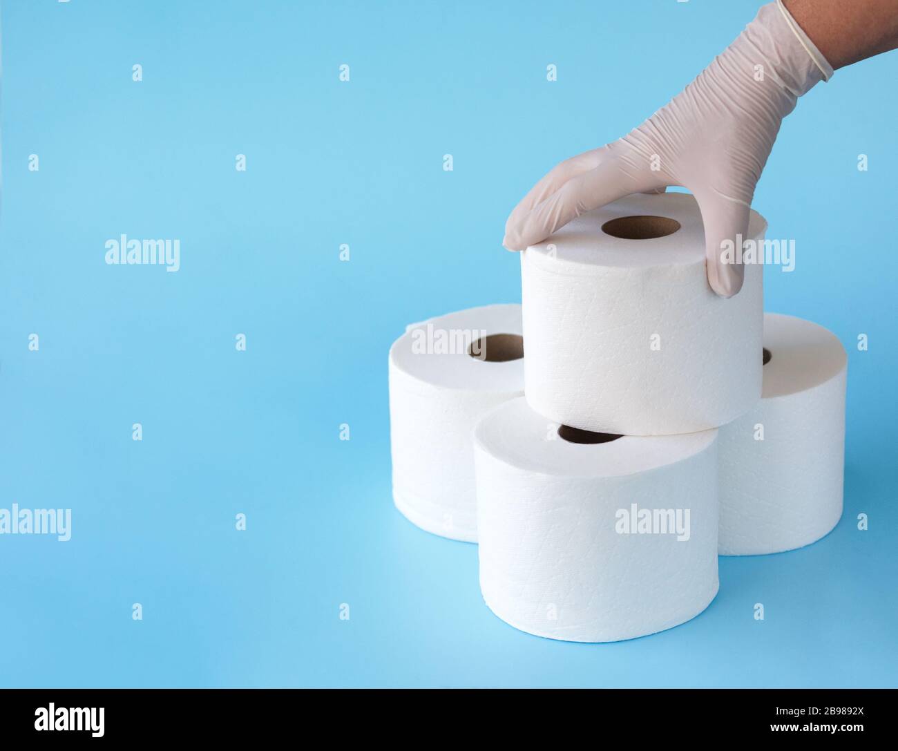Hand in medical gloves take roll of toilet paper from a tower of rolls