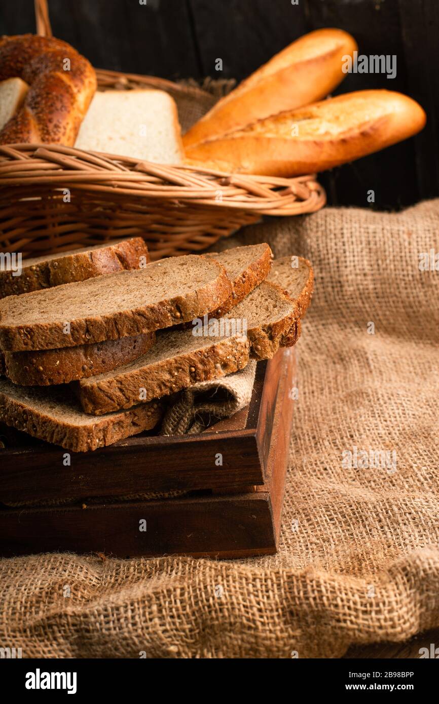Slices of brown bread in box and bagels with baguette in basket Stock Photo