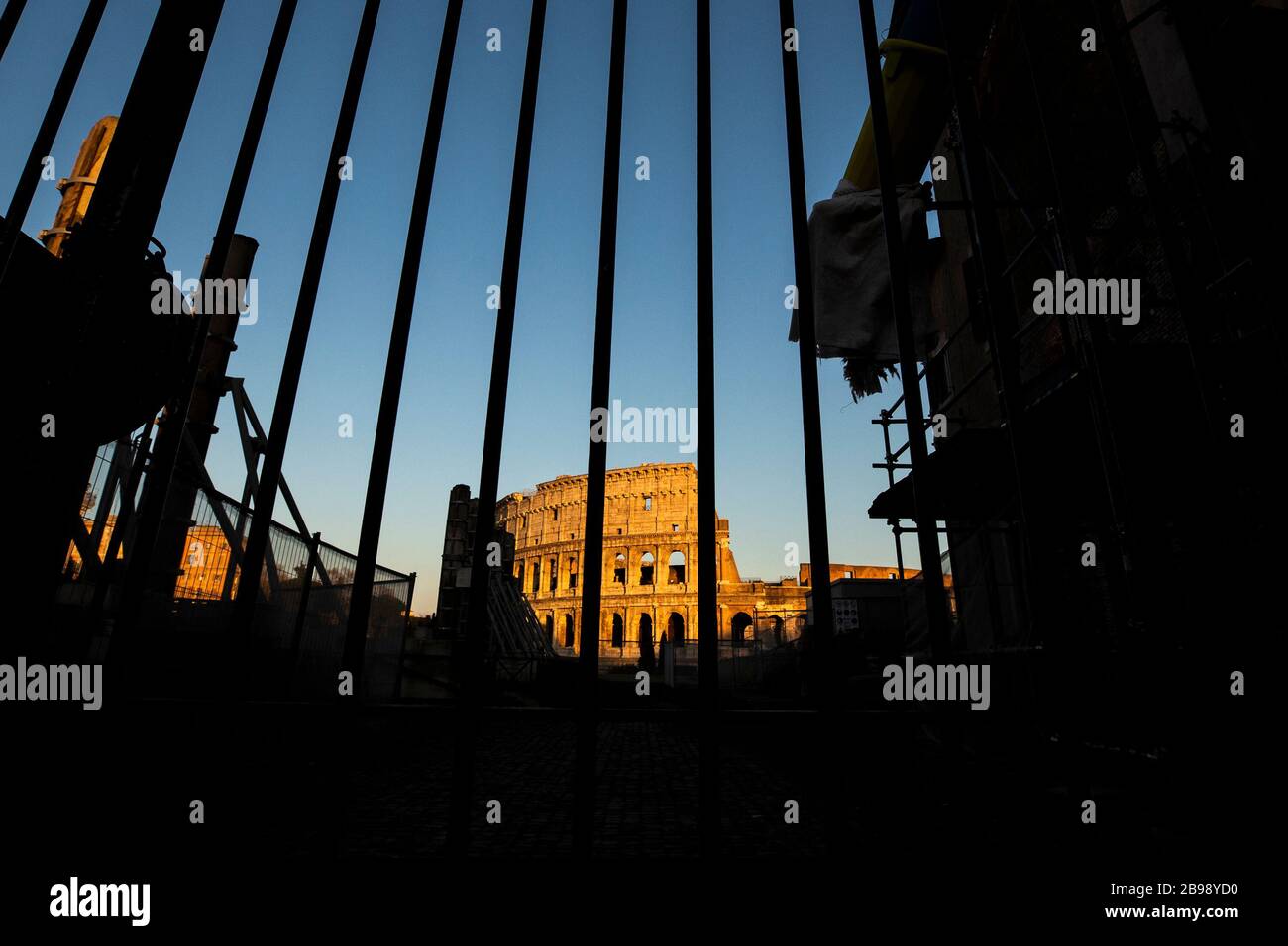 Roma, Italy. 23rd Mar, 2020. A view of the Colosseum behind a gate in Rome during the 14th day of lockdown imposed nationwide by the Italian government that tries to tackle the coronavirus outbreak. Every movements in the citiies are restricted, and streets usually filled with life and traffic are almost empty (Photo by Giuseppe Fama/Pacific Press) Credit: Pacific Press Agency/Alamy Live News Stock Photo