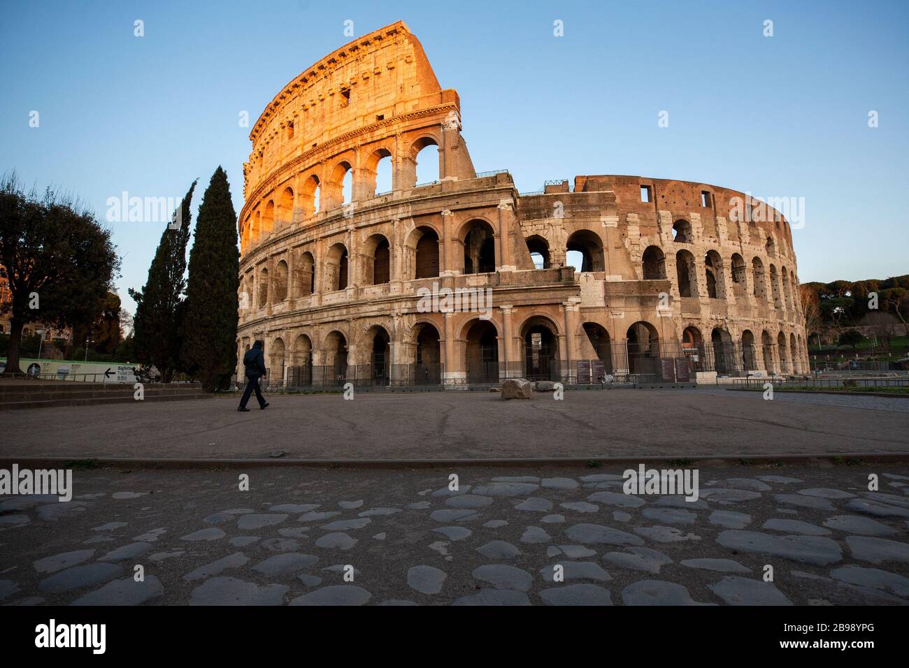 Roma, Italy. 23rd Mar, 2020. A man walks in front of the Colosseum during the 14th day of lockdown imposed nationwide by the Italian government that tries to tackle the coronavirus outbreak. Every movements in the citiies are restricted, and streets usually filled with life and traffic are almost empty (Photo by Giuseppe Fama/Pacific Press) Credit: Pacific Press Agency/Alamy Live News Stock Photo