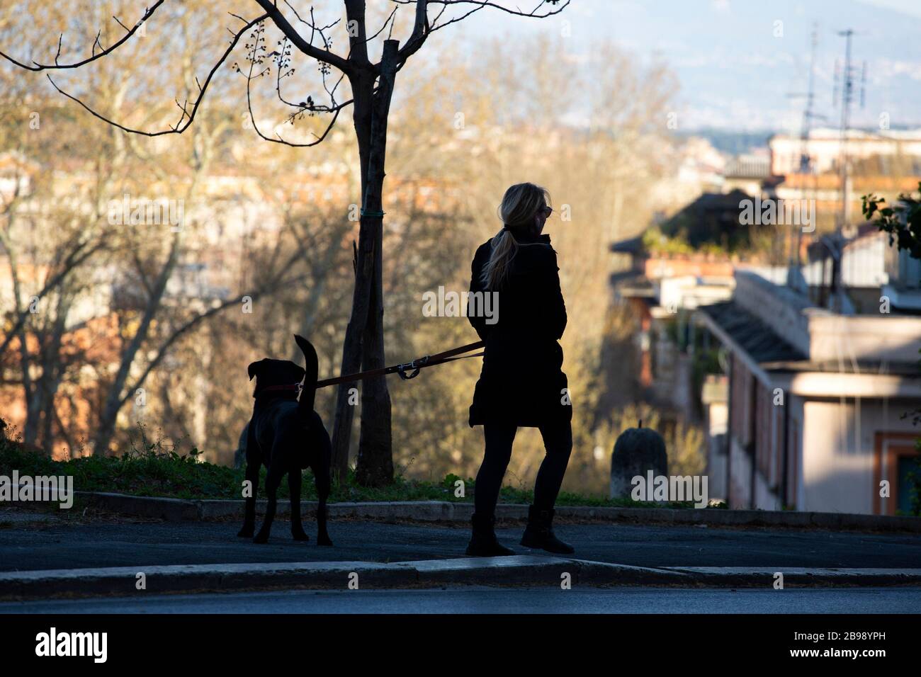 Roma, Italy. 23rd Mar, 2020. A woman walks with a dog in Rome during the 14th day of lockdown imposed nationwide by the Italian government that tries to tackle the coronavirus outbreak. Every movements in the citiies are restricted, and streets usually filled with life and traffic are almost empty (Photo by Giuseppe Fama/Pacific Press) Credit: Pacific Press Agency/Alamy Live News Stock Photo