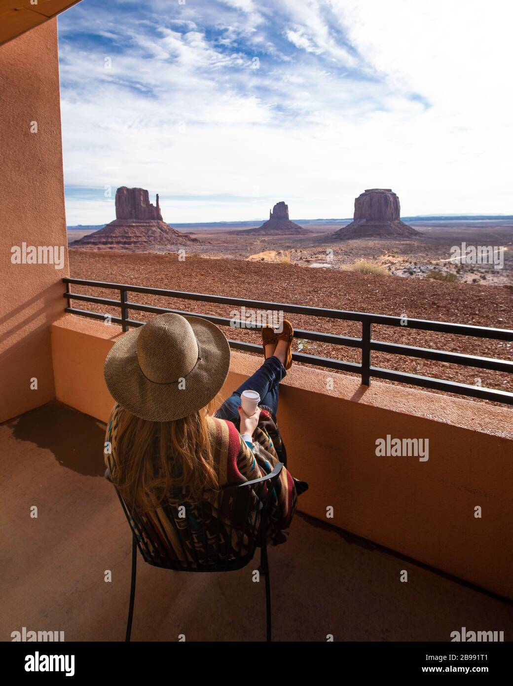 red haired girl with hat overlooking monument gallery from hotel balcony enjoying coffee Stock Photo