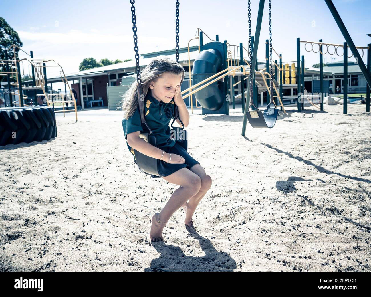 Covid-19 outbreak schools closures. Sad and bored Schoolgirl feeling depressed and lonely in empty playground as school is closed. Restrictions and lo Stock Photo