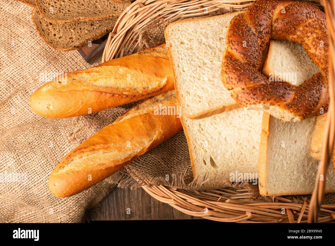 French baguette with slices of bread and bagels in basket Stock Photo