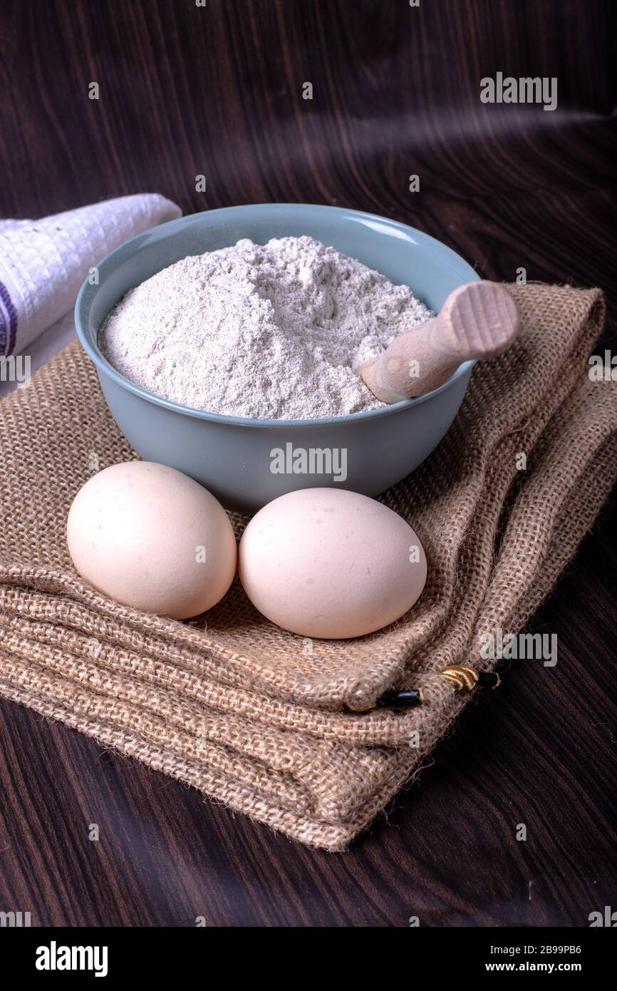 A bowl of flour with eggs on tablecloth Stock Photo