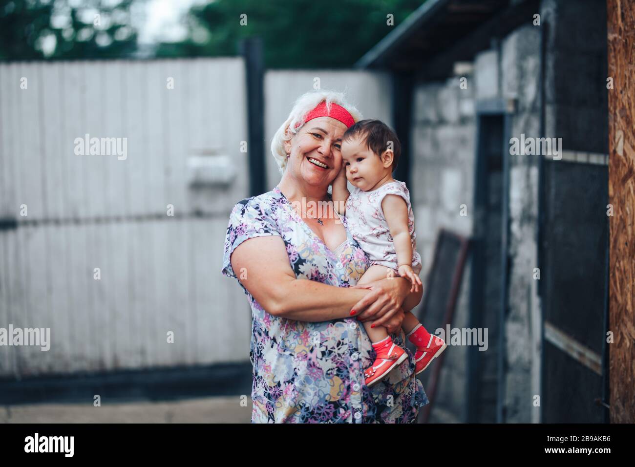 Grandmother Hugging granddaughter In nature in sunny summer day Stock Photo