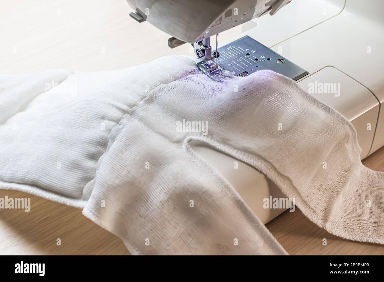 making home made breathing mask, corona virus protection. Homemade medical mask in the process. Sewing virus face mask at home. Detail on sewing machi Stock Photo