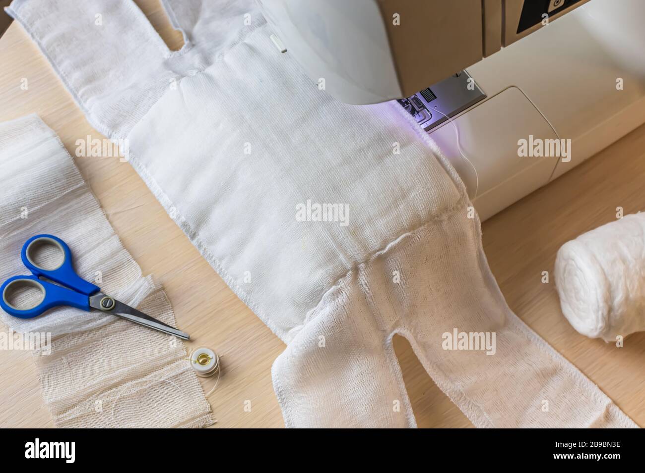 making home made breathing mask, corona virus protection. Homemade medical mask in the process. Sewing virus face mask at home. Detail on sewing machi Stock Photo