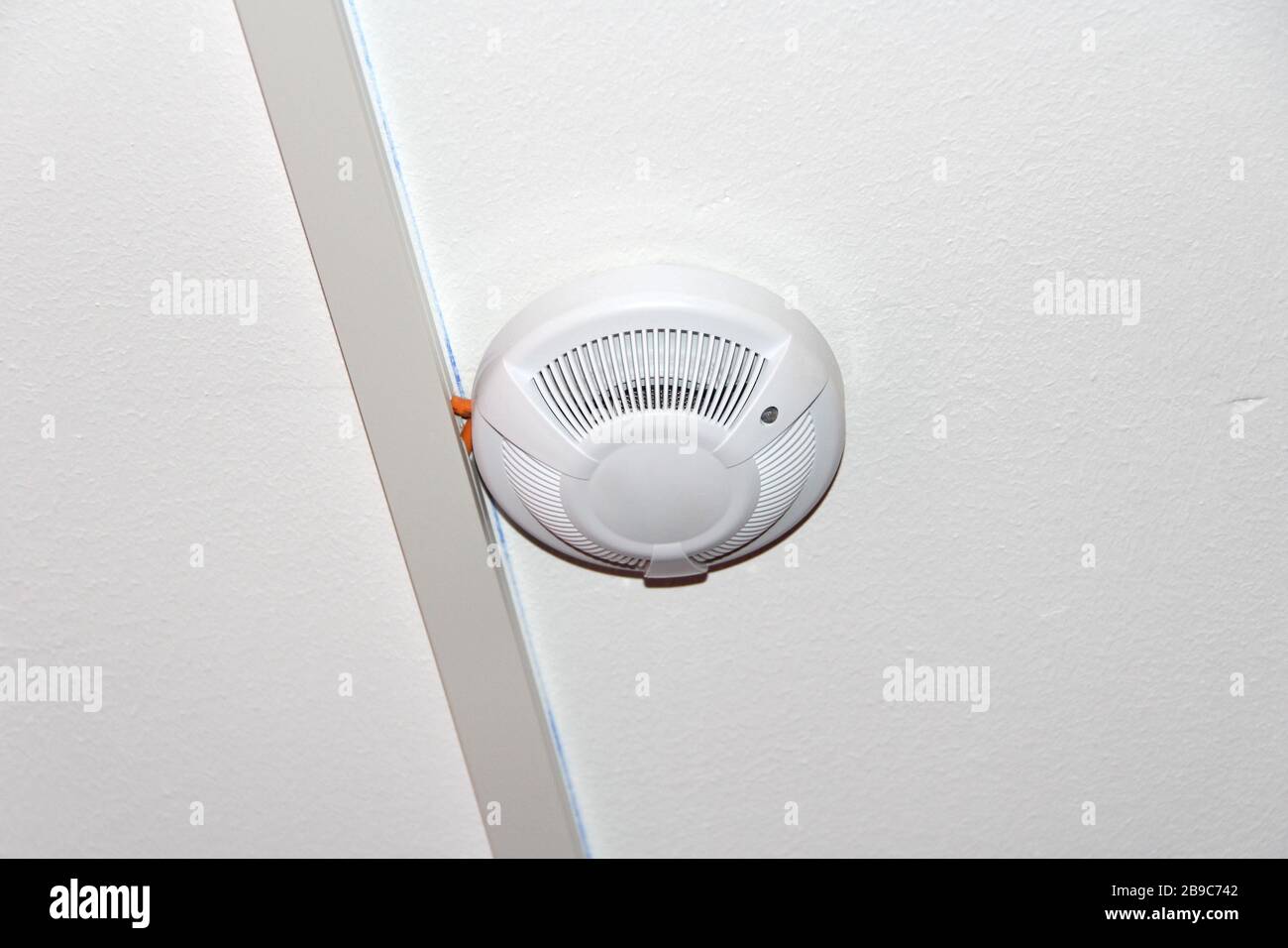 White smoke detector on the ceiling. Fire safety and alarm concept ...