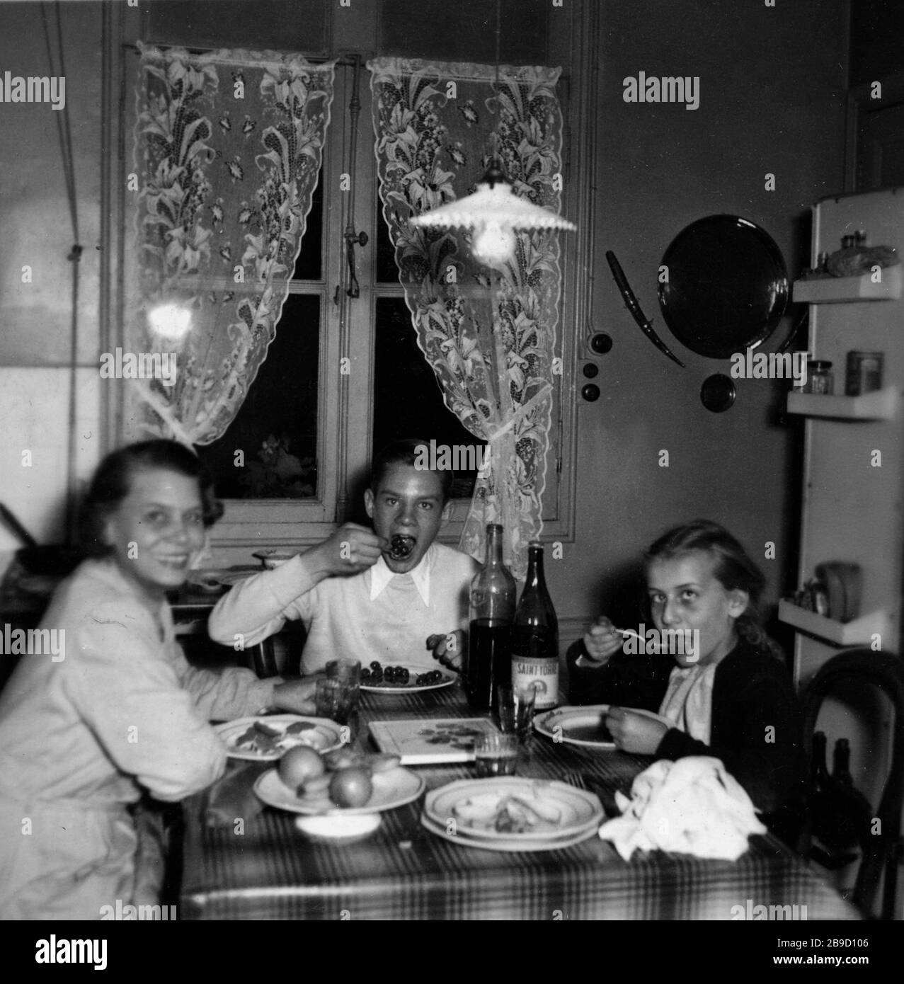 A mother and her two children at the dining table in a French kitchen. [automated translation