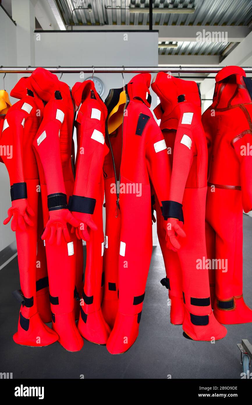 Bright red immersions suits hanging neatly in a row giving a nice esthetic look Stock Photo