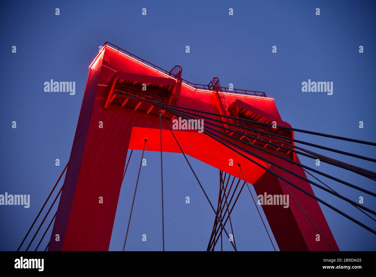 Close up top part of the bright red bridge in Rotterdam Willemsbrug early evening slightly lit up Stock Photo