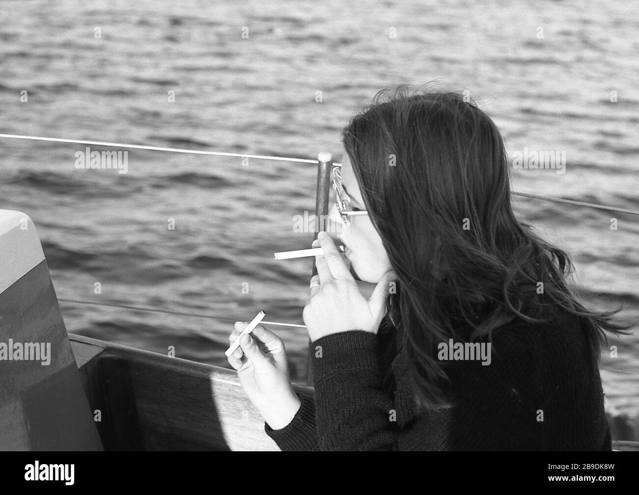 A babe woman lights a cigarette during a boat trip across the Scharmützelsee automated