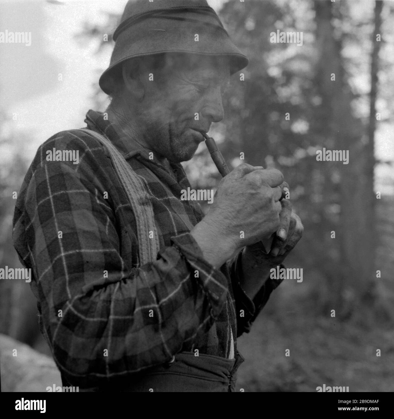 A woodcutter takes a break in the forest near Elmau near Garmisch-Partenkirchen. He lights a pipe. [automated translation] Stock Photo