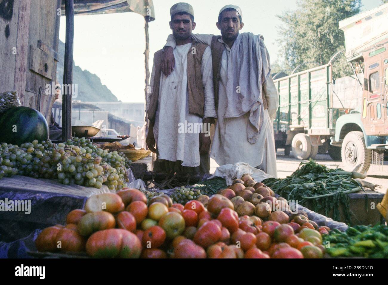 Two fruit dealers arm in arm at their stands in Torkham, Pakistan