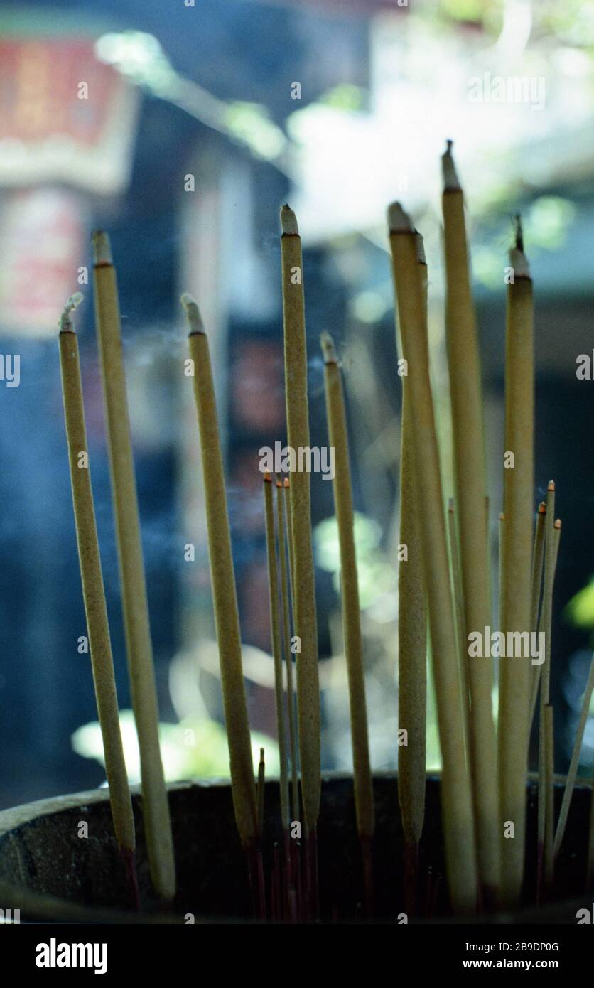 Burning incense sticks in Singapore. In the background a street can be
