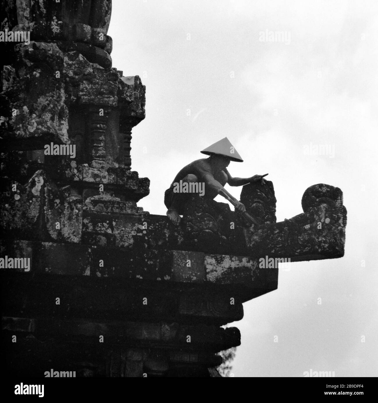 A Worker Wearing A Straw Hat On A Ledge Of The Heavily Weathered Facade