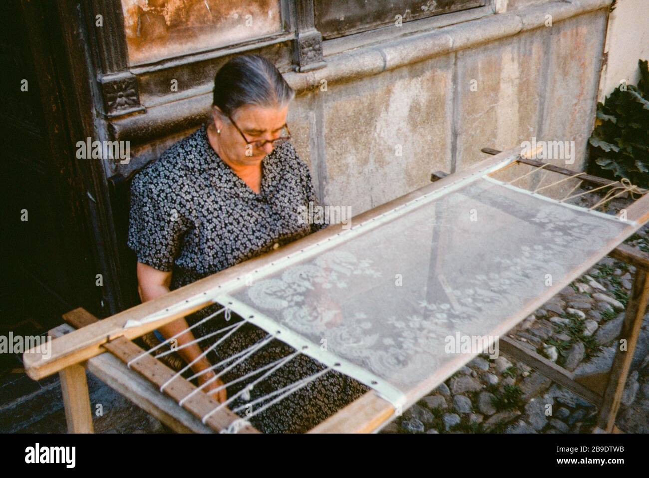 In front of a house in Granada, a stenter frame is set up on which an embroiderer is working. [automated translation] Stock Photo