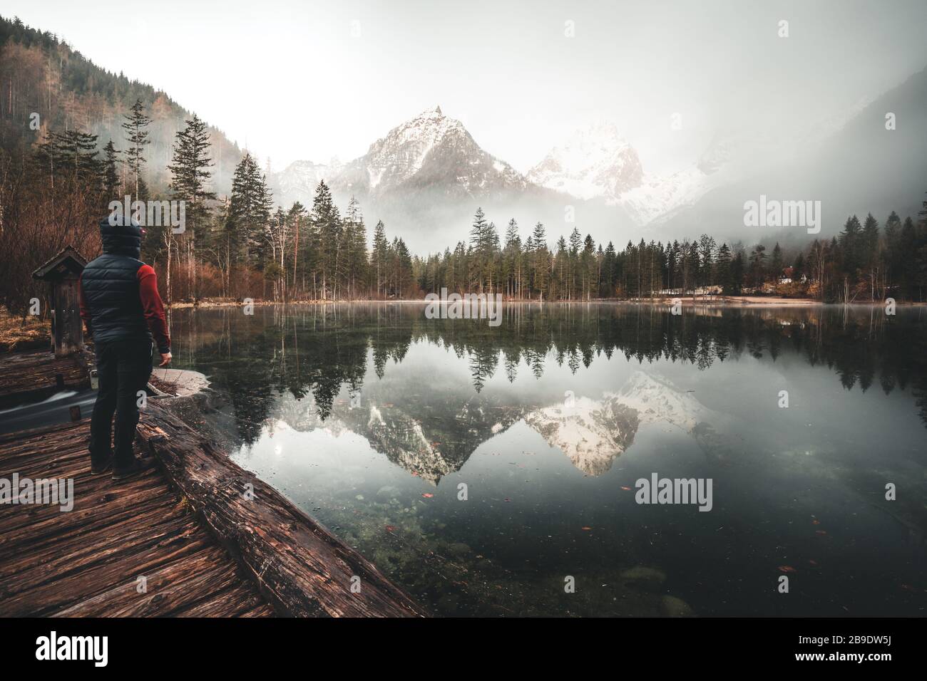 man standing at a mountain lake enjoying the sunrise in the austrian alps near Hinterstoder Stock Photo