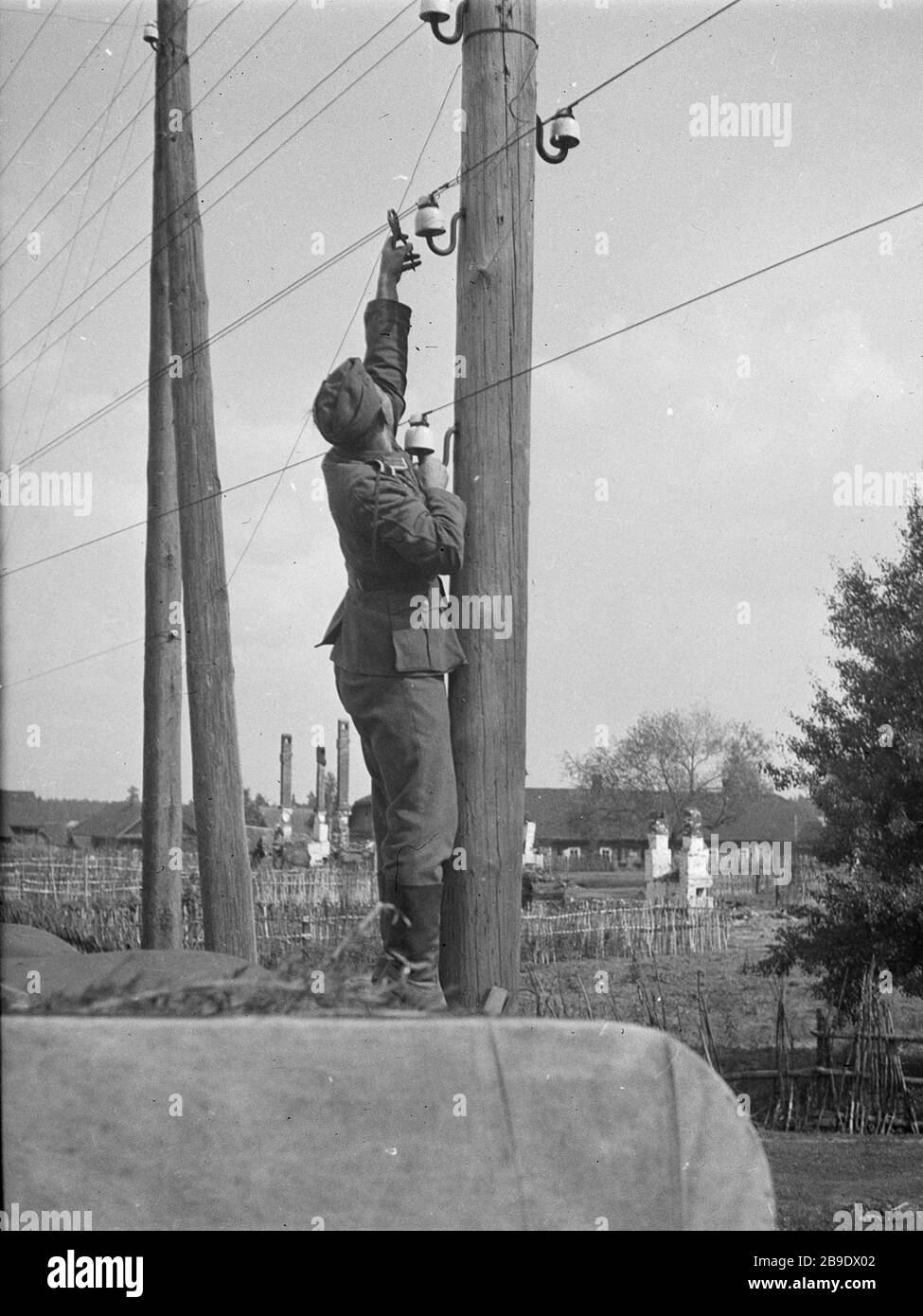 Standing on the roof of the truck, a sergeant repairs the telephone