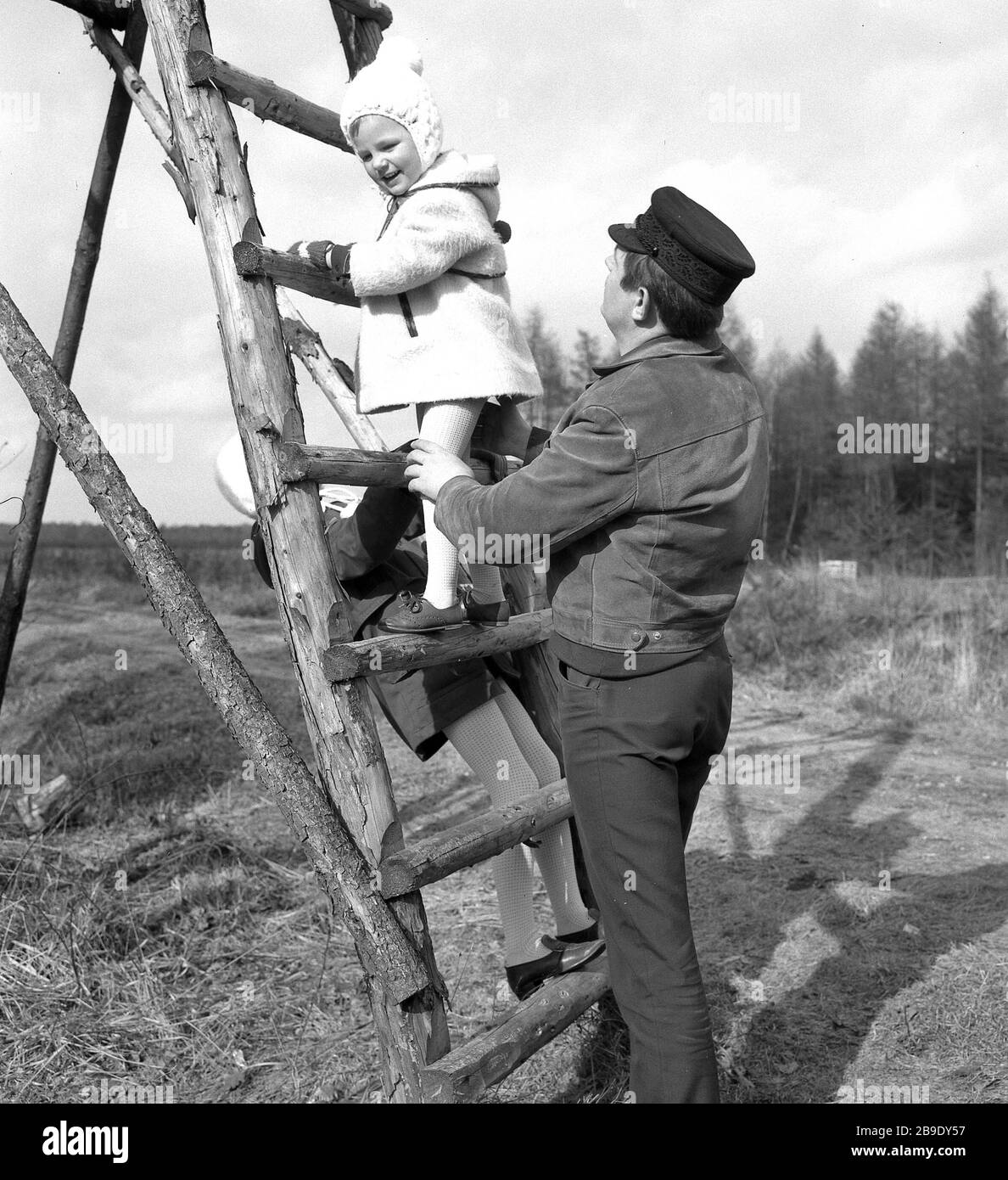 Two girls climb the ladder of a hunter's stand in the heath near