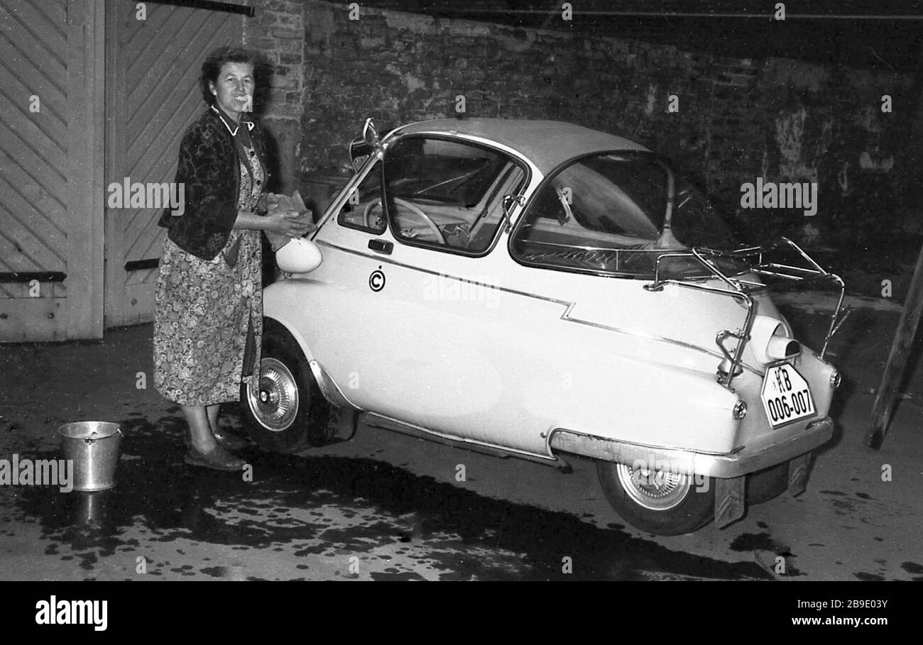 A woman cleans a BMW Isetta in Berlin-Charlottenburg. The BMW Isetta is a scooter car built between 1955 and 1962.   [automated translation] Stock Photo