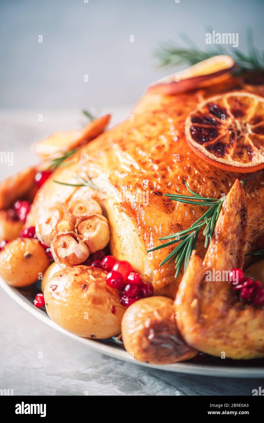 Roasted chicken with oranges, rosemary and cranberries on plate over concrete background. Traditional Thanksgiving or Friendsgiving holiday celebratio Stock Photo