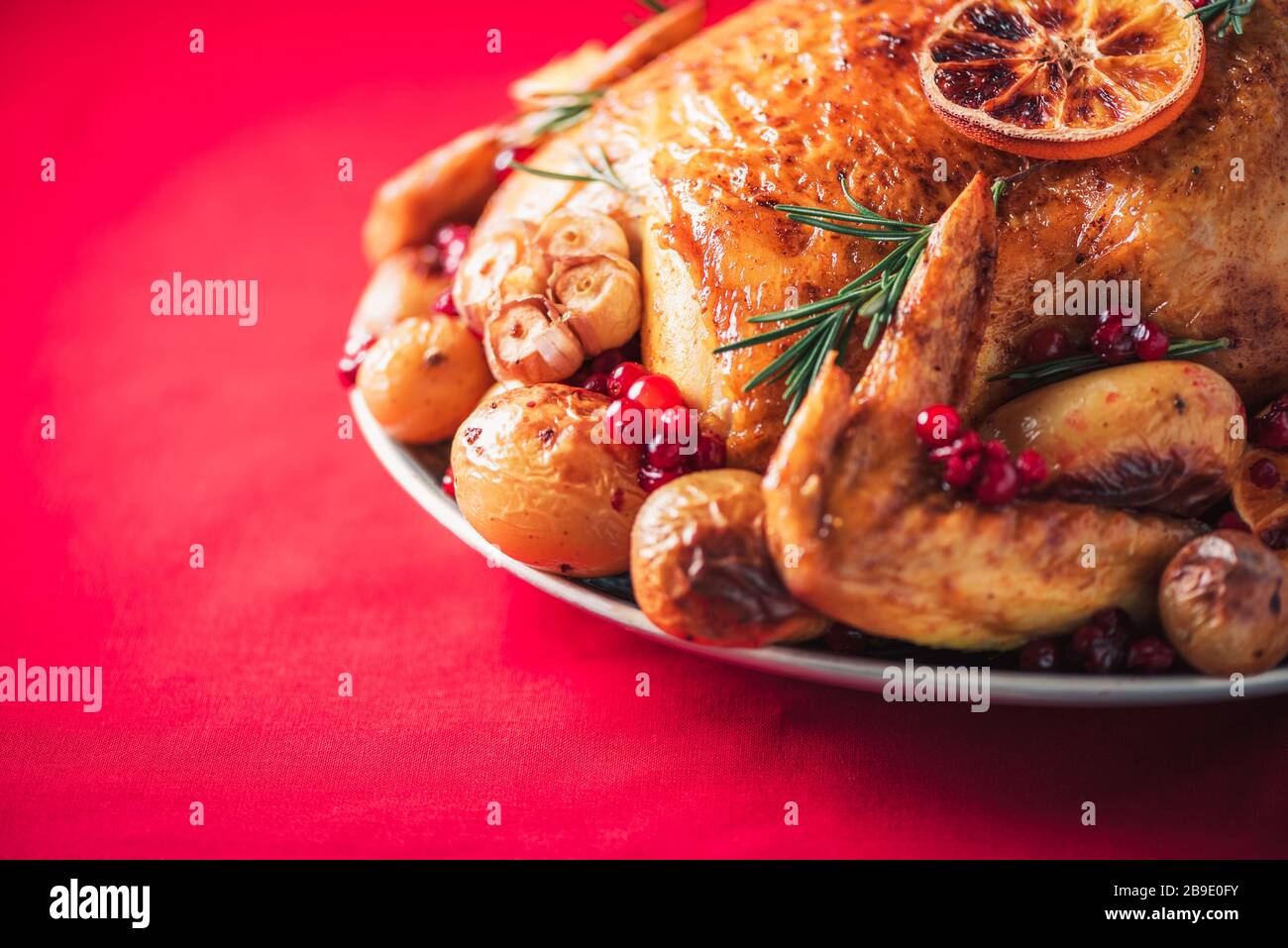 Roasted chicken with oranges, rosemary and cranberries on plate over ...