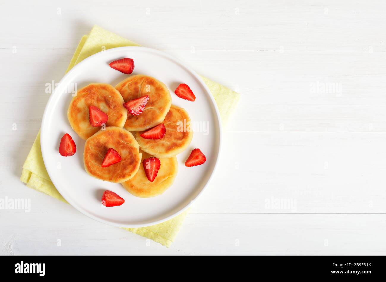 Cottage cheese pancakes with strawberry, syrniki on white background. Top view, flat lay Stock Photo