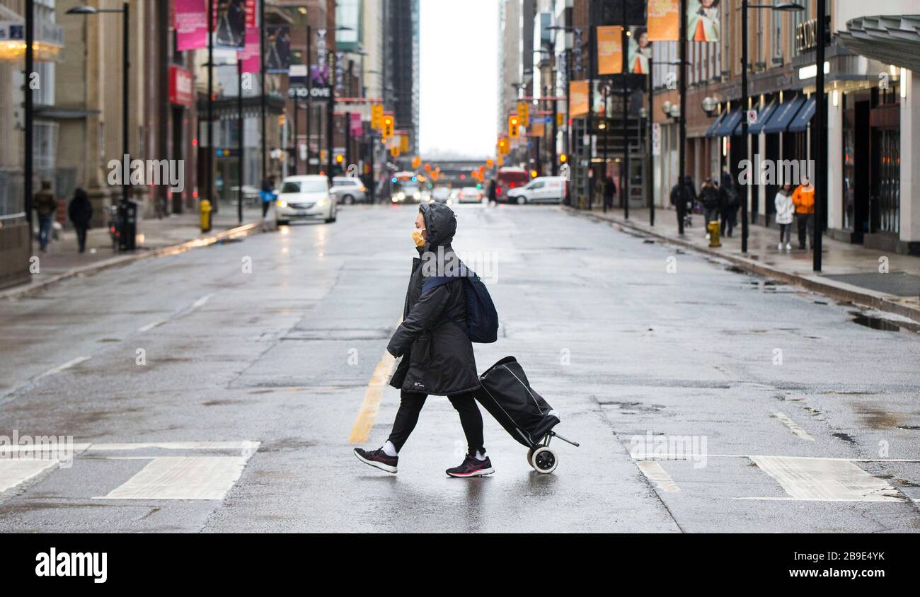 (200324) -- TORONTO, March 24, 2020 (Xinhua) -- A woman wearing a face mask crosses a street in Toronto, Canada, March 23, 2020.  Canadian Prime Minister Justin Trudeau announced Monday that his government will allot 192 million Canadian dollars (132 million U.S. dollars) on the development and production of vaccines and treatments against COVID-19. (Photo by Zou Zheng/Xinhua) Stock Photo