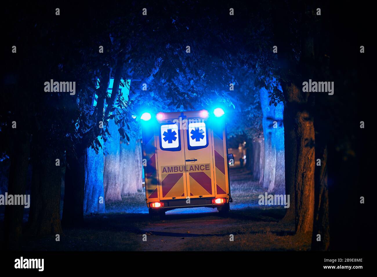 Rear view of ambulance of emergency medical service against dark alley. Themes rescue, hope and health care. Stock Photo