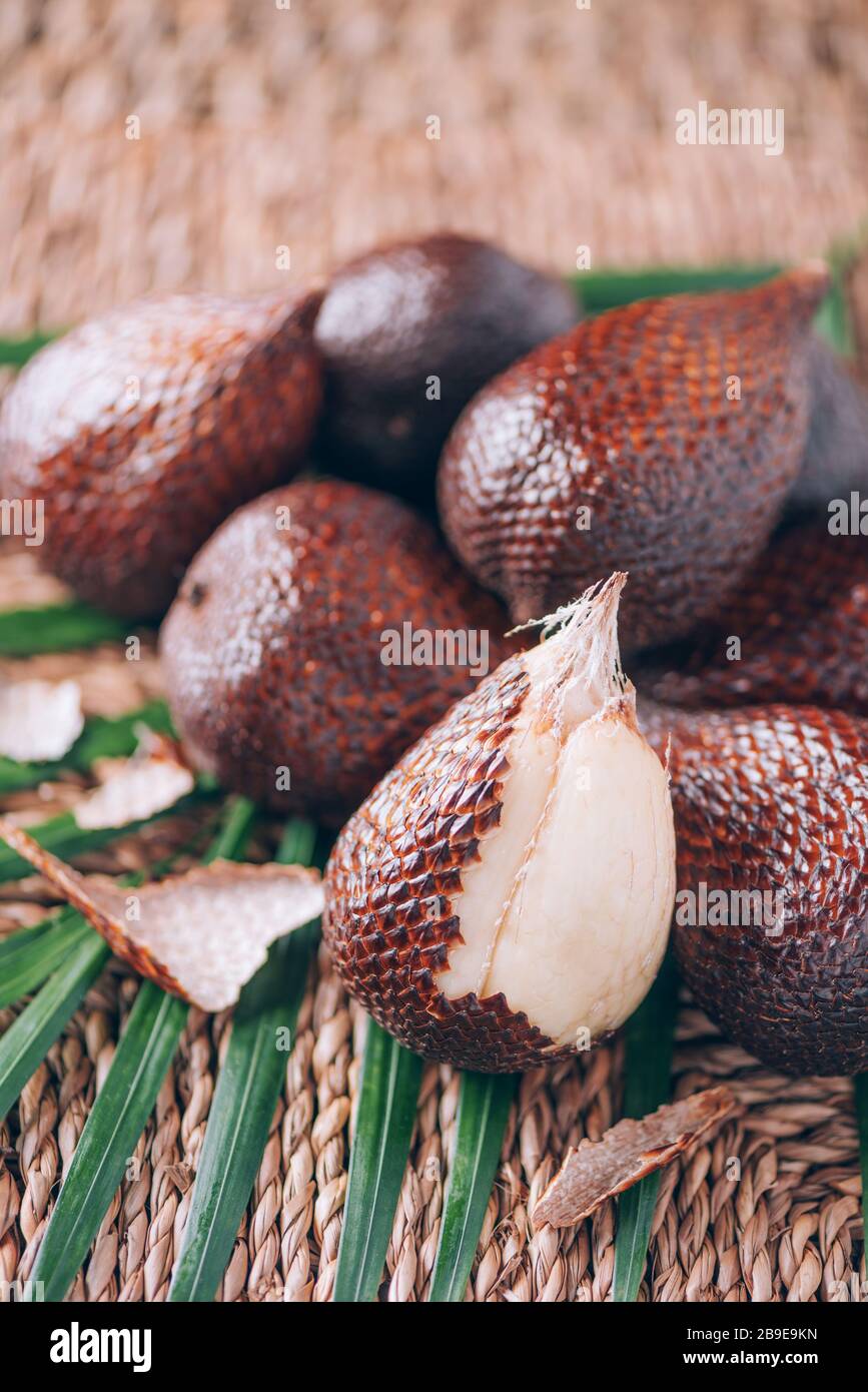 Red Salacca. Salak, snake fruits with palm leaves on rattan background