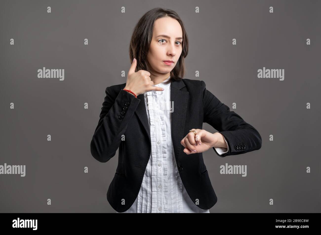 Portrait Of Wonderful Young Business Woman Wering Black Suit And Shirt Showing Call Me Gesture And Looking Her Watch Poseing On Isolated Gray Backgrou Stock Photo Alamy Portrait Of Wonderful Young Business Woman Wering Black Suit And Shirt Showing Call Me Gesture And Looking Her Watch Poseing On Isolated Gray Backgrou Stock Photo Alamy
