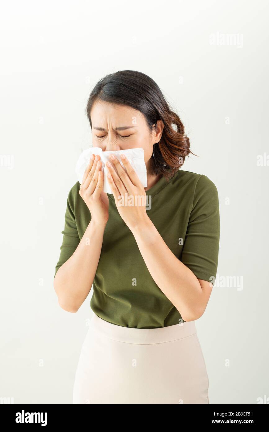Woman with a cold blowing her runny nose with tissue Stock Photo