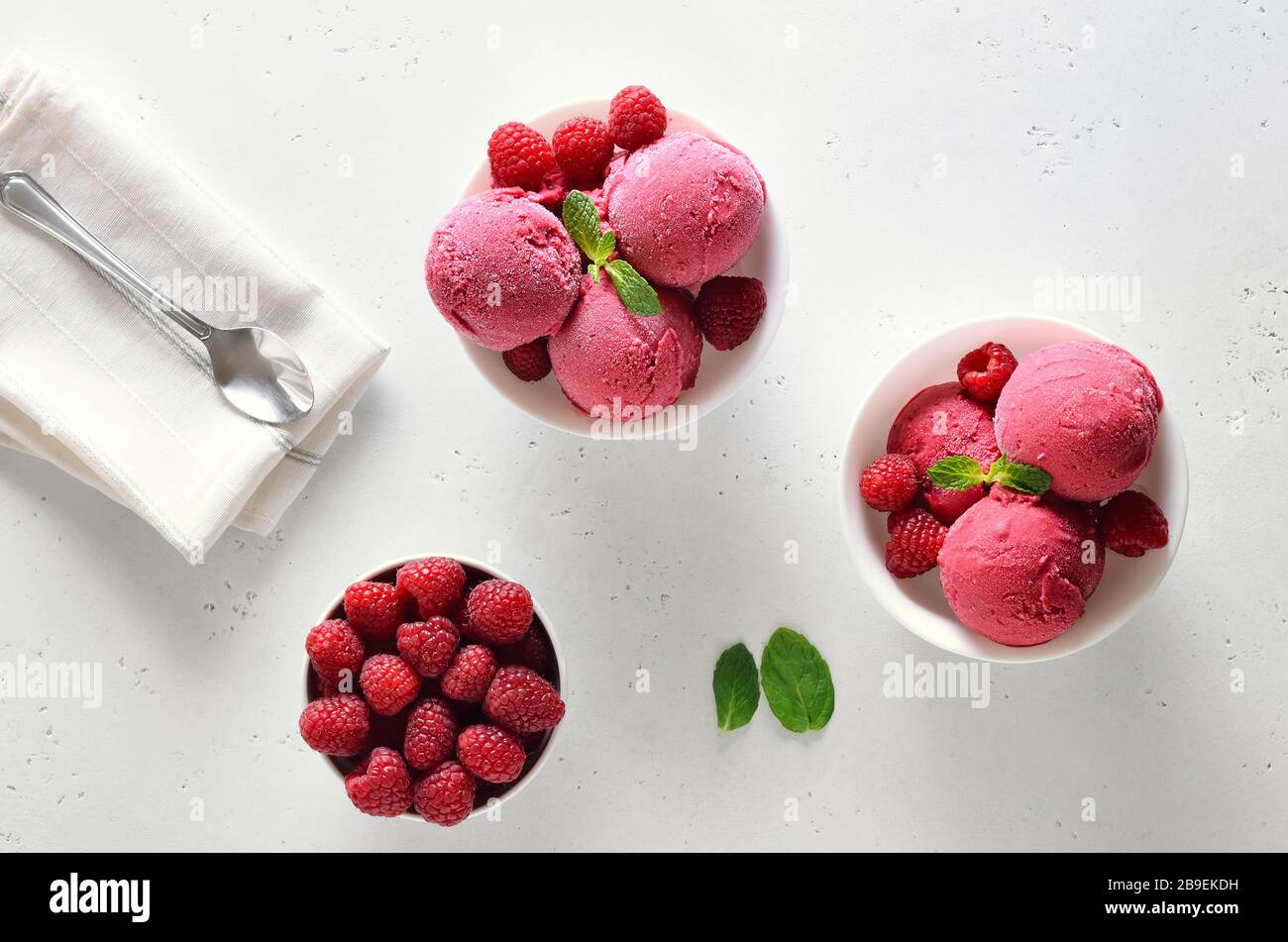 Raspberry ice cream scoop with fresh raspberries in bowl and fresh raspberries over white stone background with free text space. Top view, flat lay Stock Photo