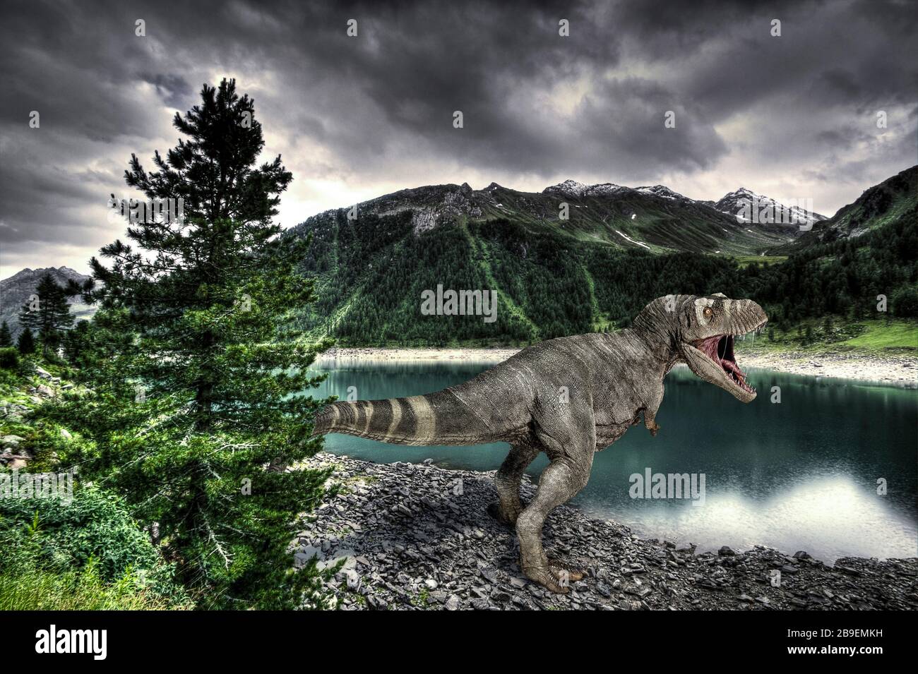 T-Rex dinosaur on a lake shore, with mountains in the background. Stock Photo