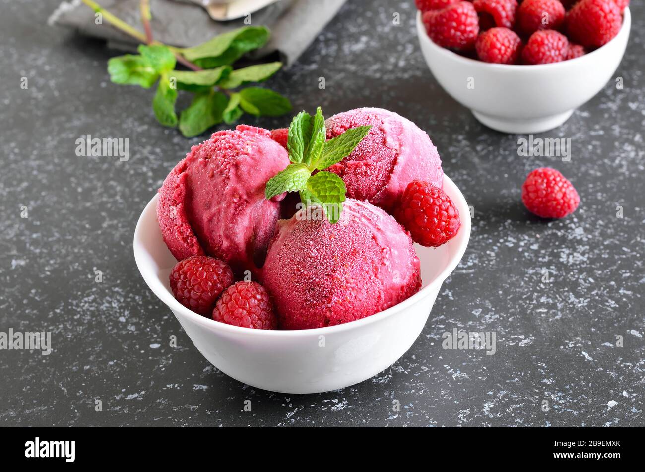 Raspberry ice cream scoop with fresh raspberries in bowl on stone background. Cold summer dessert Stock Photo