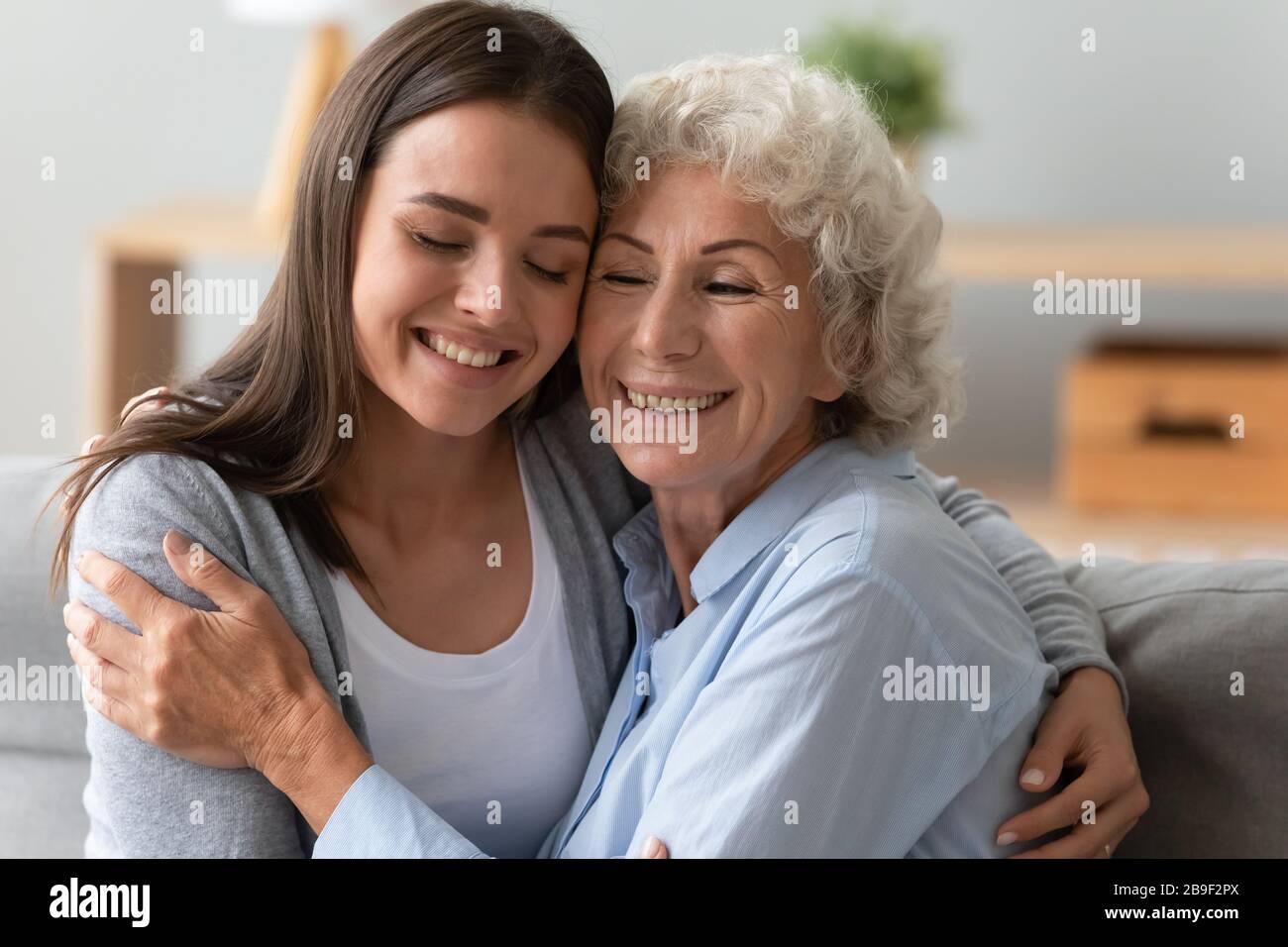 Smiling elderly mom and adult daughter enjoy home moment Stock Photo