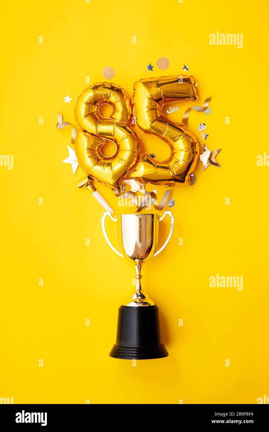 Number 85 gold anniversary celebration balloon exploding from a winning trophy Stock Photo