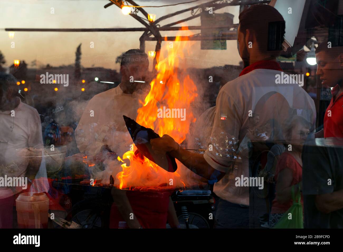 Busy evening scene of Moroccan men cooking barbecue dinner on an open fire at the famous Djemaa el Fna square, November 6, 2017, Marrakech, Morocco. D Stock Photo